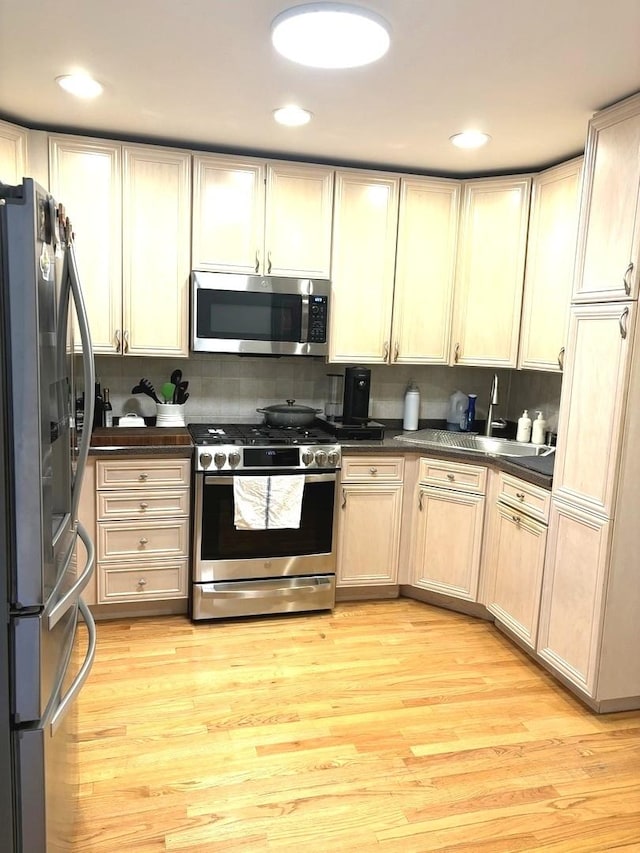 kitchen with decorative backsplash, appliances with stainless steel finishes, and light hardwood / wood-style flooring