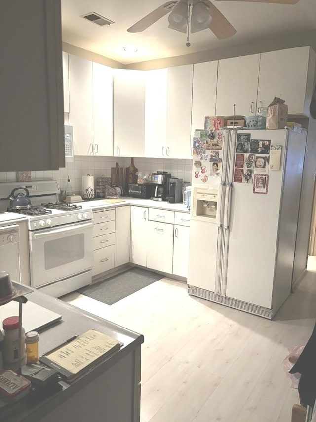 kitchen featuring white appliances, white cabinets, ceiling fan, light wood-type flooring, and tasteful backsplash