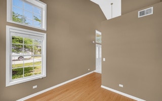 unfurnished room featuring light hardwood / wood-style floors, a high ceiling, and a wealth of natural light