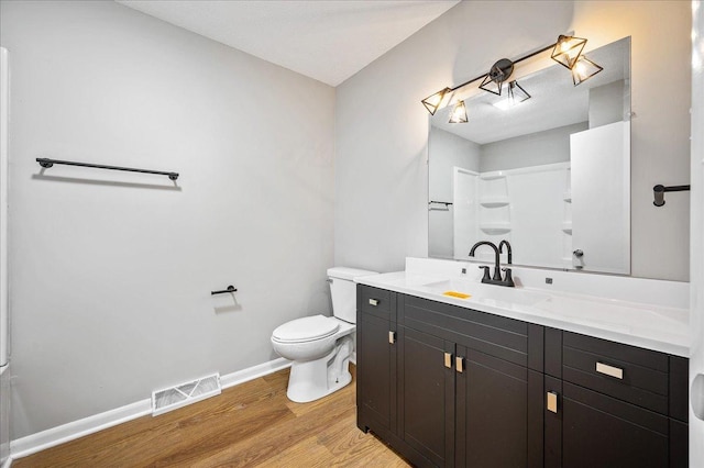 bathroom featuring walk in shower, vanity, wood-type flooring, and toilet