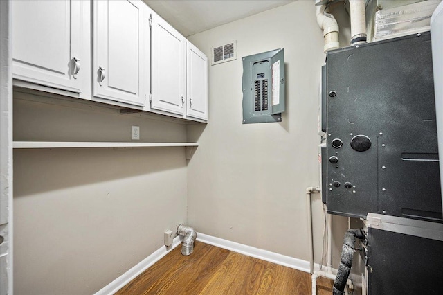 clothes washing area featuring electric panel and wood-type flooring