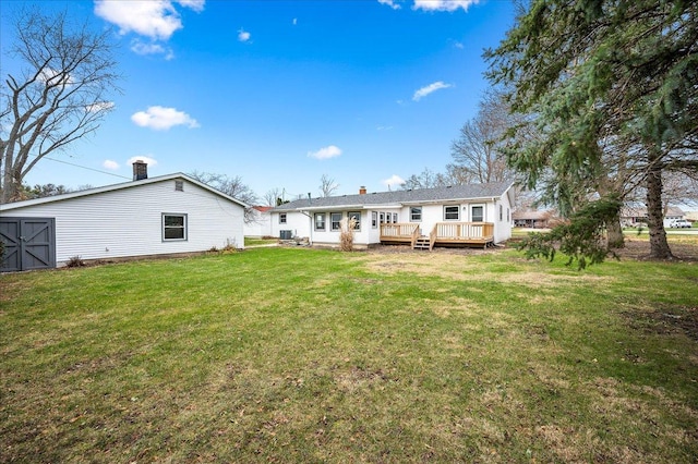 rear view of house with a lawn and a wooden deck