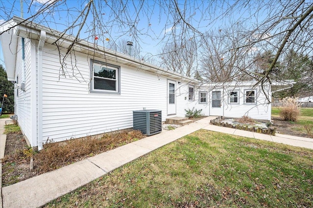 back of property with central AC unit and a lawn