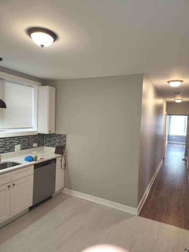 kitchen featuring stainless steel dishwasher, light wood-type flooring, white cabinetry, and tasteful backsplash