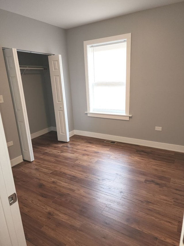 unfurnished bedroom featuring dark hardwood / wood-style floors and a closet