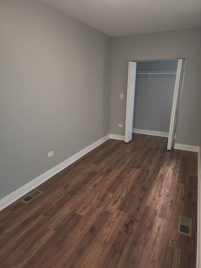 unfurnished bedroom with a closet and dark wood-type flooring