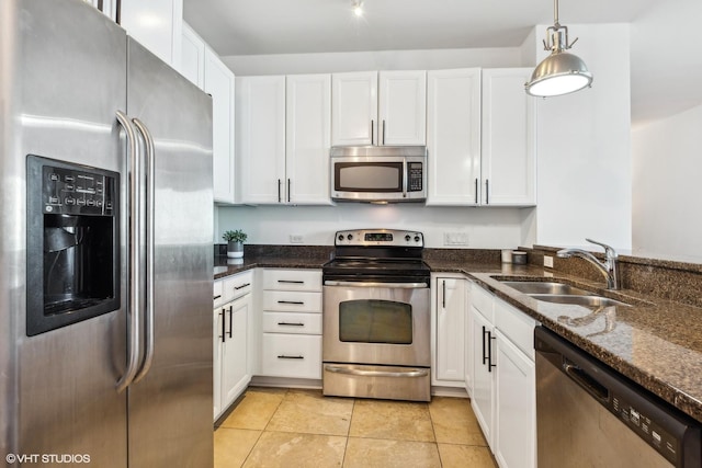 kitchen with white cabinetry, sink, hanging light fixtures, dark stone counters, and appliances with stainless steel finishes