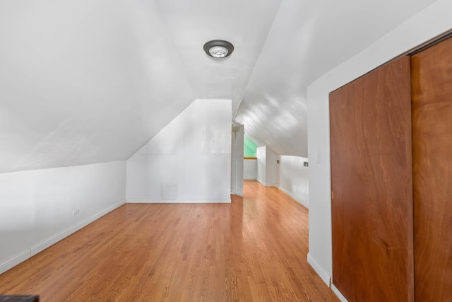 additional living space with light hardwood / wood-style floors and lofted ceiling