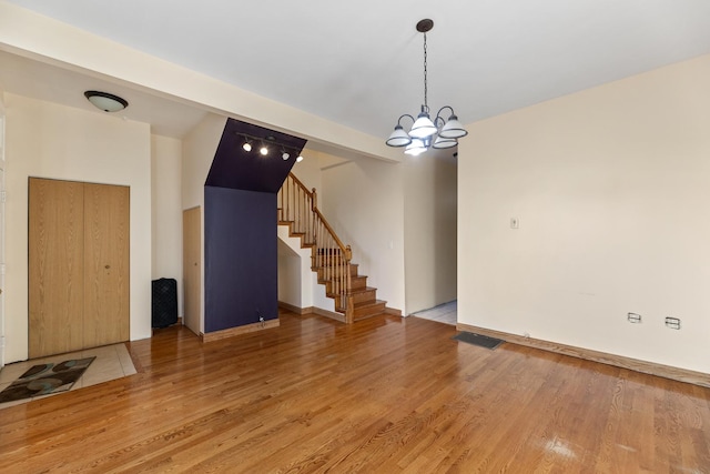 unfurnished room with wood-type flooring and a notable chandelier