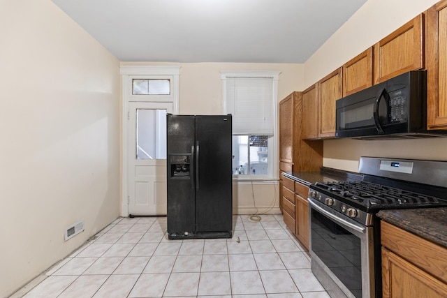 kitchen featuring black appliances, dark stone countertops, and light tile patterned floors