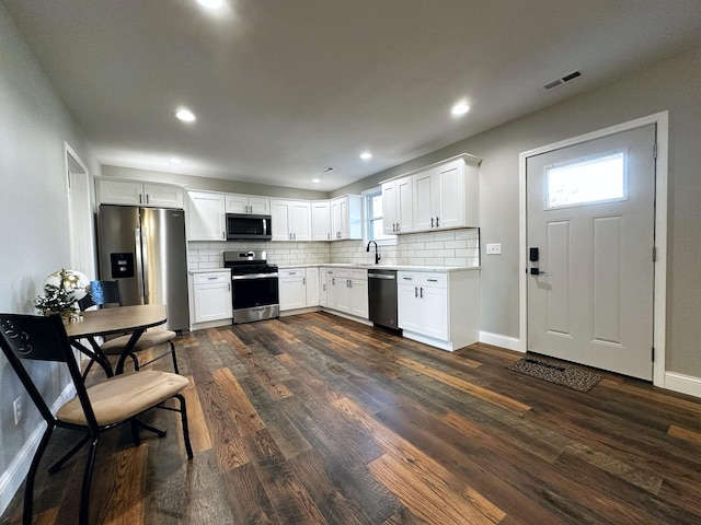 kitchen featuring backsplash, dark wood-type flooring, sink, white cabinetry, and stainless steel appliances