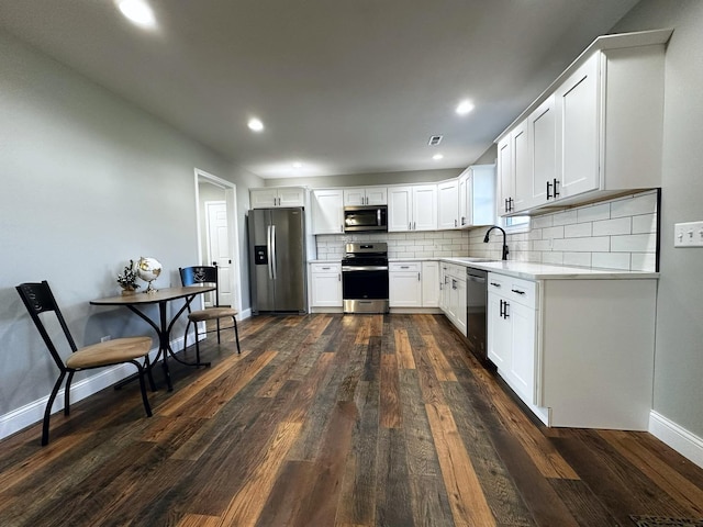 kitchen featuring decorative backsplash, appliances with stainless steel finishes, dark hardwood / wood-style flooring, sink, and white cabinetry