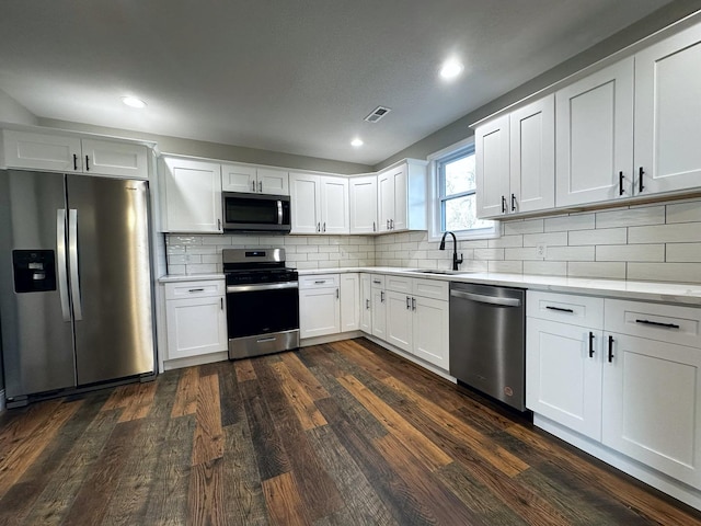 kitchen with sink, white cabinetry, stainless steel appliances, and dark wood-type flooring