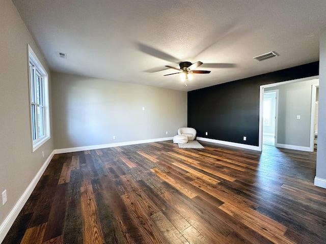 spare room featuring a healthy amount of sunlight and dark hardwood / wood-style flooring