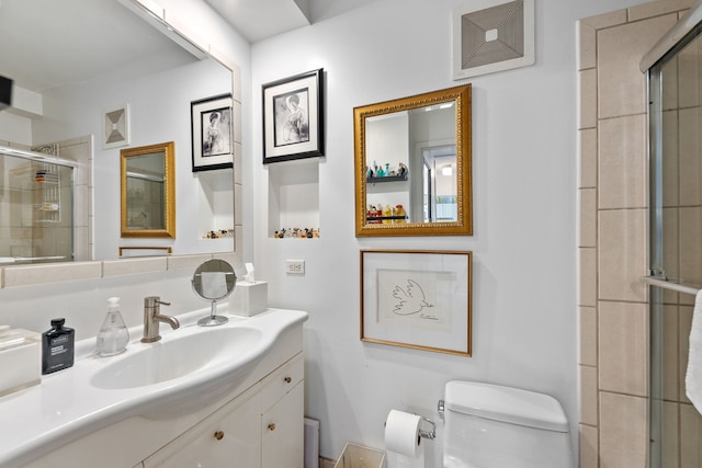 bathroom featuring vanity, toilet, and a shower with shower door