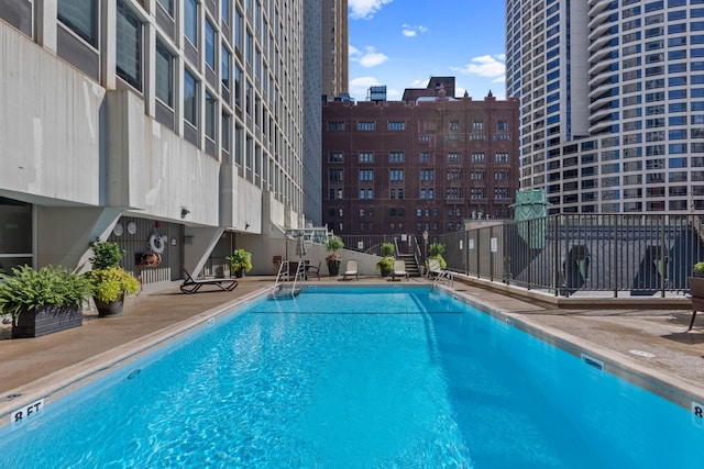 view of pool featuring a water view, a patio, and a view of the beach