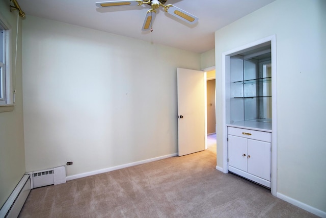 carpeted empty room with ceiling fan and a baseboard heating unit