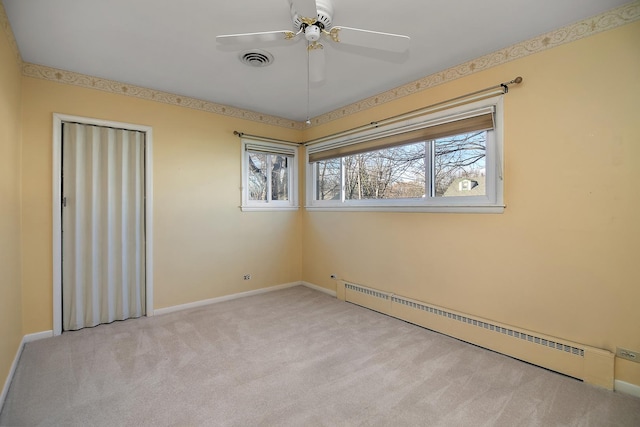 spare room featuring ceiling fan, light colored carpet, and a baseboard heating unit