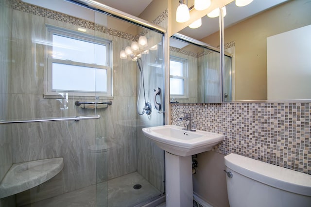 bathroom featuring sink, tasteful backsplash, toilet, a shower with door, and tile walls