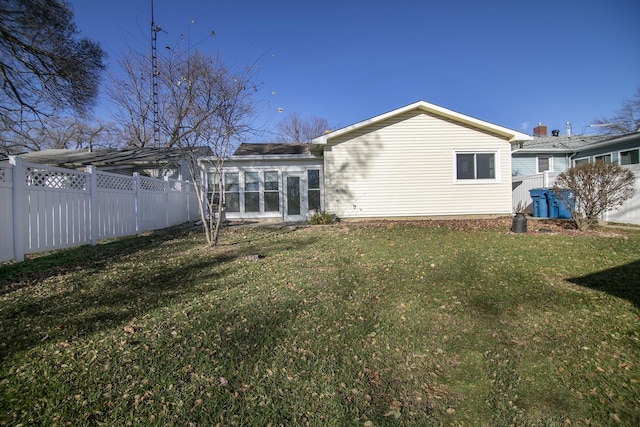 rear view of property featuring a lawn and a sunroom