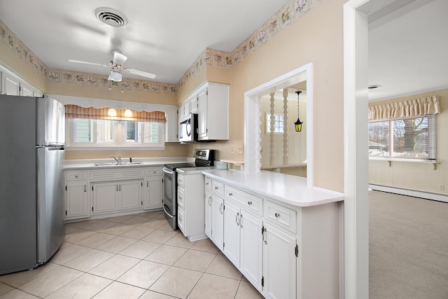 kitchen with light carpet, stainless steel appliances, baseboard heating, ceiling fan, and white cabinetry