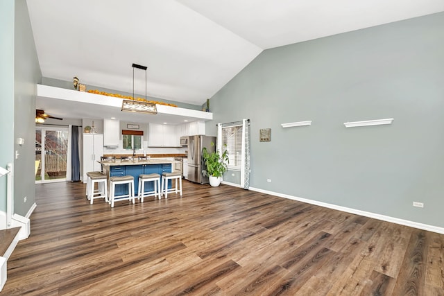 kitchen with appliances with stainless steel finishes, vaulted ceiling, hardwood / wood-style floors, hanging light fixtures, and a breakfast bar area