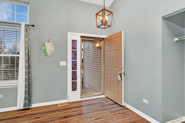 entrance foyer featuring wood-type flooring, a high ceiling, and a notable chandelier