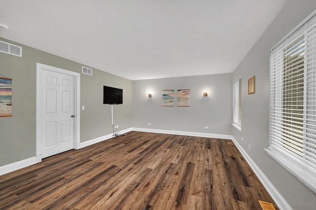 unfurnished room featuring a healthy amount of sunlight and dark wood-type flooring