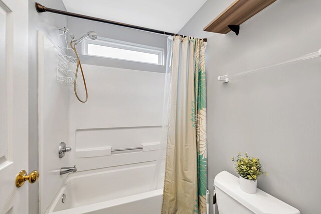 bathroom with shower / bath combination with curtain and toilet