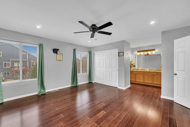 unfurnished bedroom featuring ceiling fan, a closet, dark hardwood / wood-style flooring, and ensuite bath