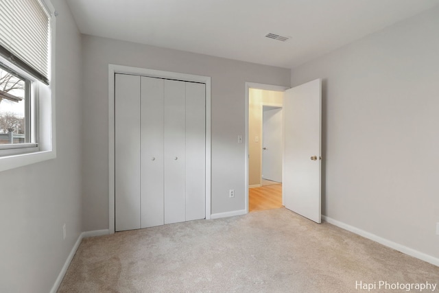 unfurnished bedroom featuring a closet and light colored carpet