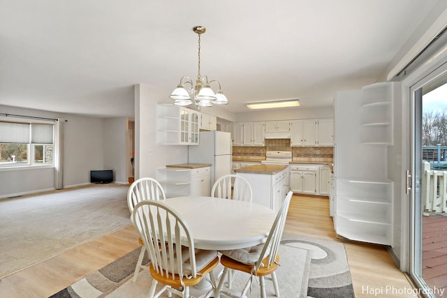 dining space with light wood-type flooring and an inviting chandelier