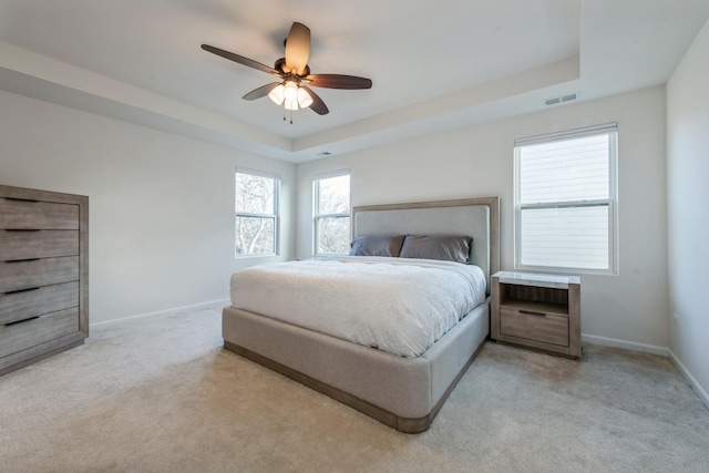 carpeted bedroom with ceiling fan and a raised ceiling