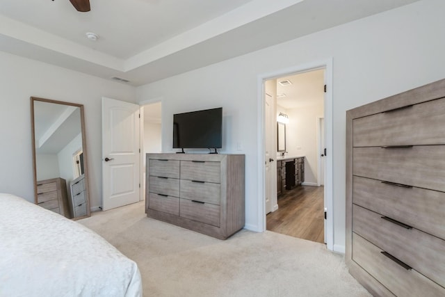 bedroom featuring ceiling fan, light colored carpet, and connected bathroom