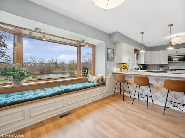 kitchen featuring a kitchen bar, a water view, white cabinets, and a healthy amount of sunlight