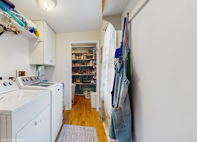 laundry room featuring cabinets, separate washer and dryer, and light hardwood / wood-style flooring