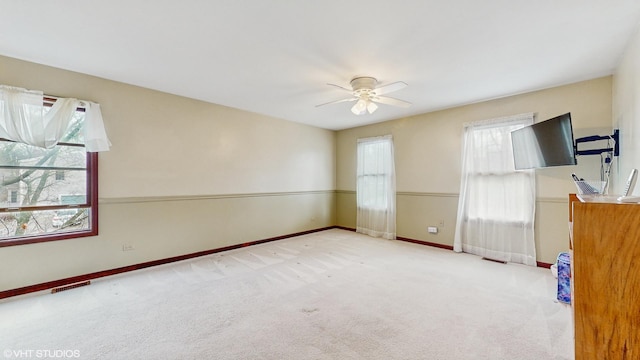 unfurnished room featuring plenty of natural light, ceiling fan, and light colored carpet