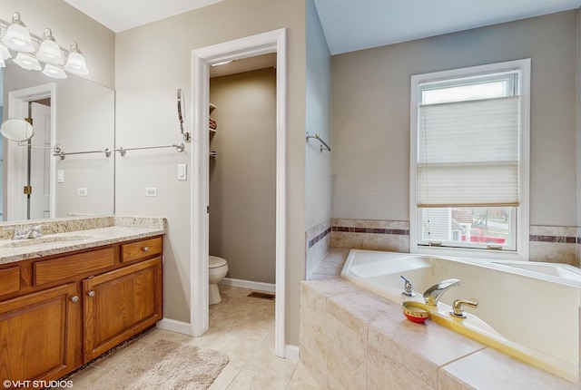 bathroom featuring tile patterned flooring, vanity, toilet, and tiled bath