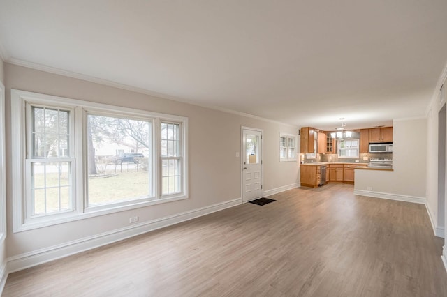 unfurnished living room with light hardwood / wood-style flooring, a wealth of natural light, and crown molding