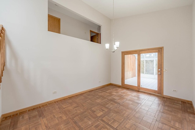 spare room with parquet flooring, a towering ceiling, and a notable chandelier