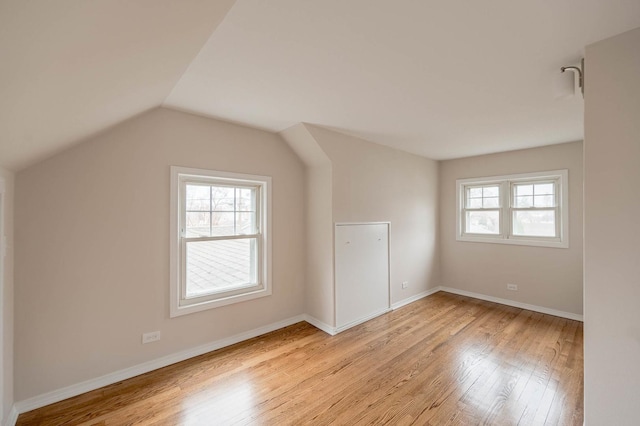 additional living space with light hardwood / wood-style floors and vaulted ceiling