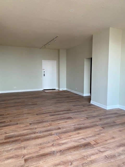 spare room with a textured ceiling, rail lighting, and light hardwood / wood-style flooring