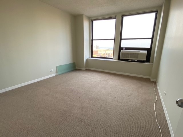 empty room featuring cooling unit, carpet, and a textured ceiling