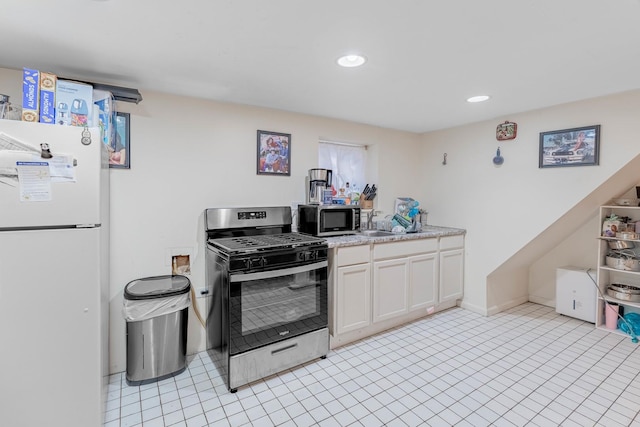 kitchen with white cabinets, light tile patterned floors, stainless steel appliances, and sink