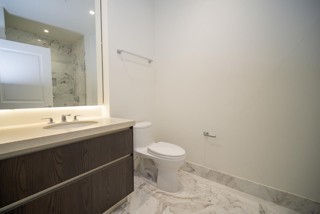 bathroom with tiled shower, vanity, and toilet