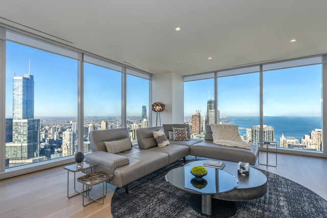 living area with a healthy amount of sunlight, a view of city, expansive windows, and wood finished floors