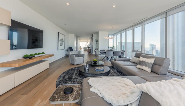 living room featuring baseboards, floor to ceiling windows, wood finished floors, and a chandelier