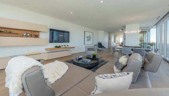 living room featuring plenty of natural light, wood finished floors, and an inviting chandelier