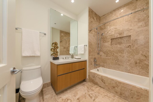 full bath featuring vanity, tiled shower / bath, and toilet