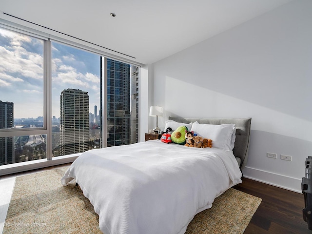 bedroom with expansive windows and dark hardwood / wood-style floors